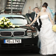 Braut und Brüutigam vor ihrem Hochzeitsauto